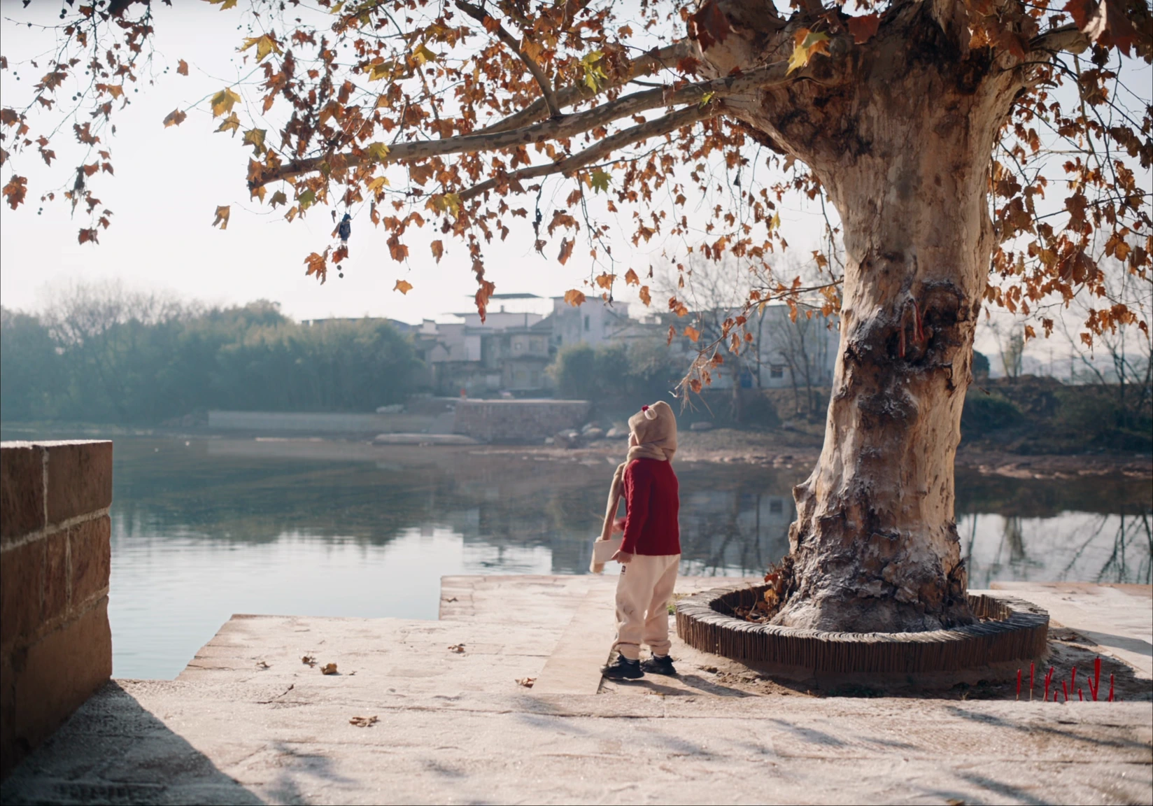 The great tree by the lake, and the child small beside it, looking up